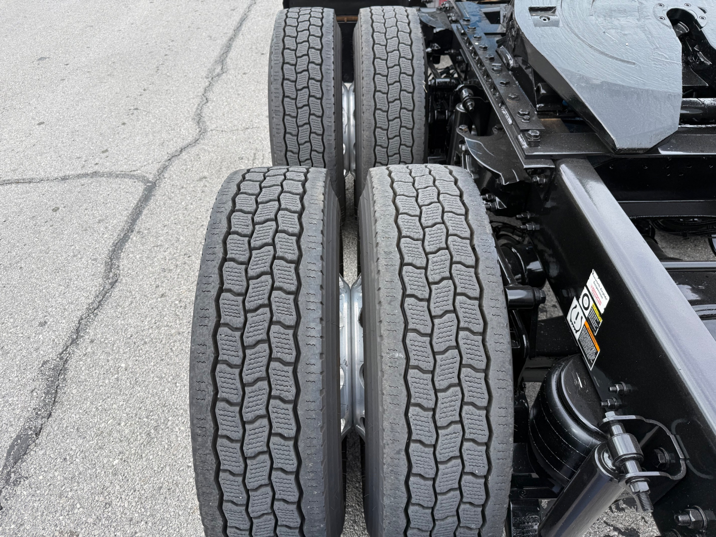 Kenworth truck rear dual tires and suspension components visible in a truck yard.