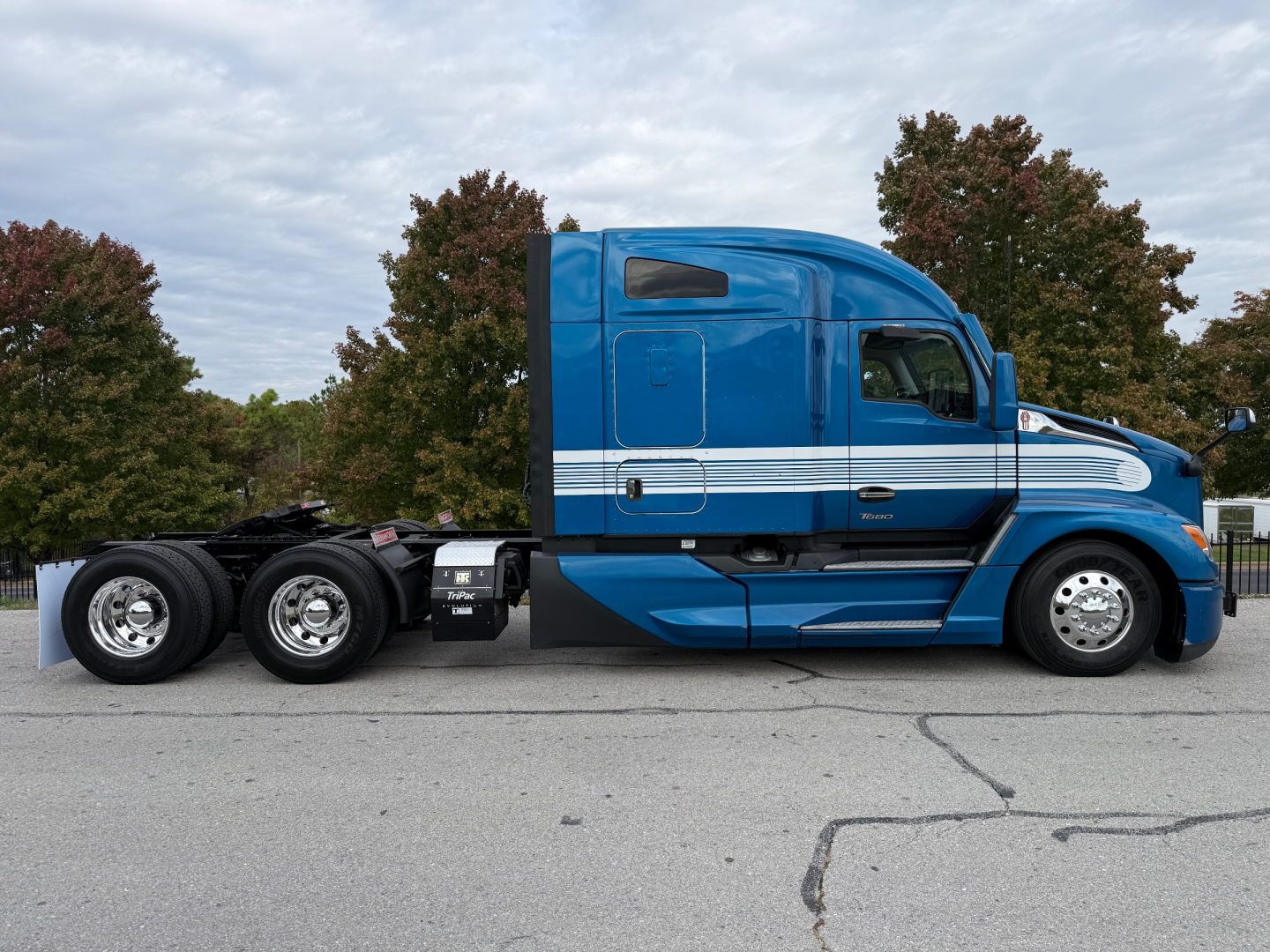 Kenworth T680 tractor in blue showing side profile with sleeper cab and chrome wheels.