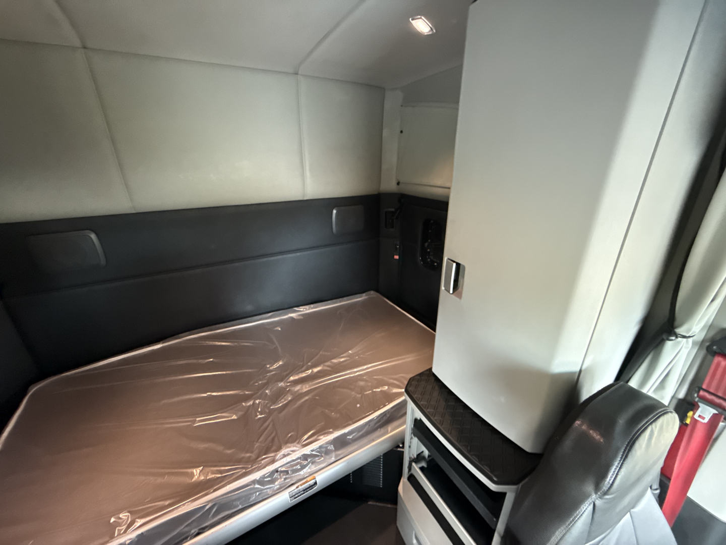 Kenworth T680 sleeper cab interior showing a bed with plastic cover and storage cabinet