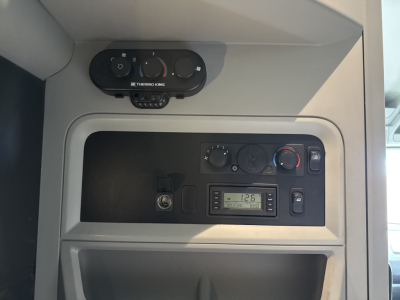 Trucker’s dashboard window showing climate controls, RPM gauge, and digital display in Kenworth T680 cab interior.