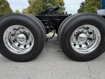 Kenworth T680 chassis with dual rear axles and chrome wheels showing tires and wheel hubs; portion of frame and fifth wheel visible.