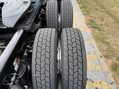 Kenworth T680 chassis rear view showing dual rear axles and twin tires on a concrete lot.