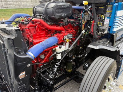 Kenworth T680 engine bay showing red engine with blue intercooler hose, multiple hoses and components in view.