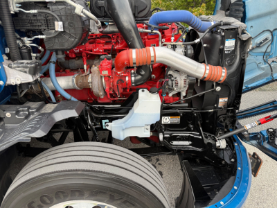 Kenworth T680 engine bay showing red diesel engine, blue coolant hoses, intake piping, and turbocharger within open-front view.