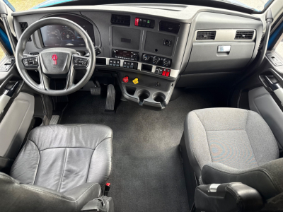 Kenworth T680 cab interior showing steering wheel, dash, and center console with switches and gauges.