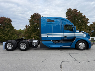 Kenworth T680 tractor in blue showing side profile with sleeper cab and chrome wheels.