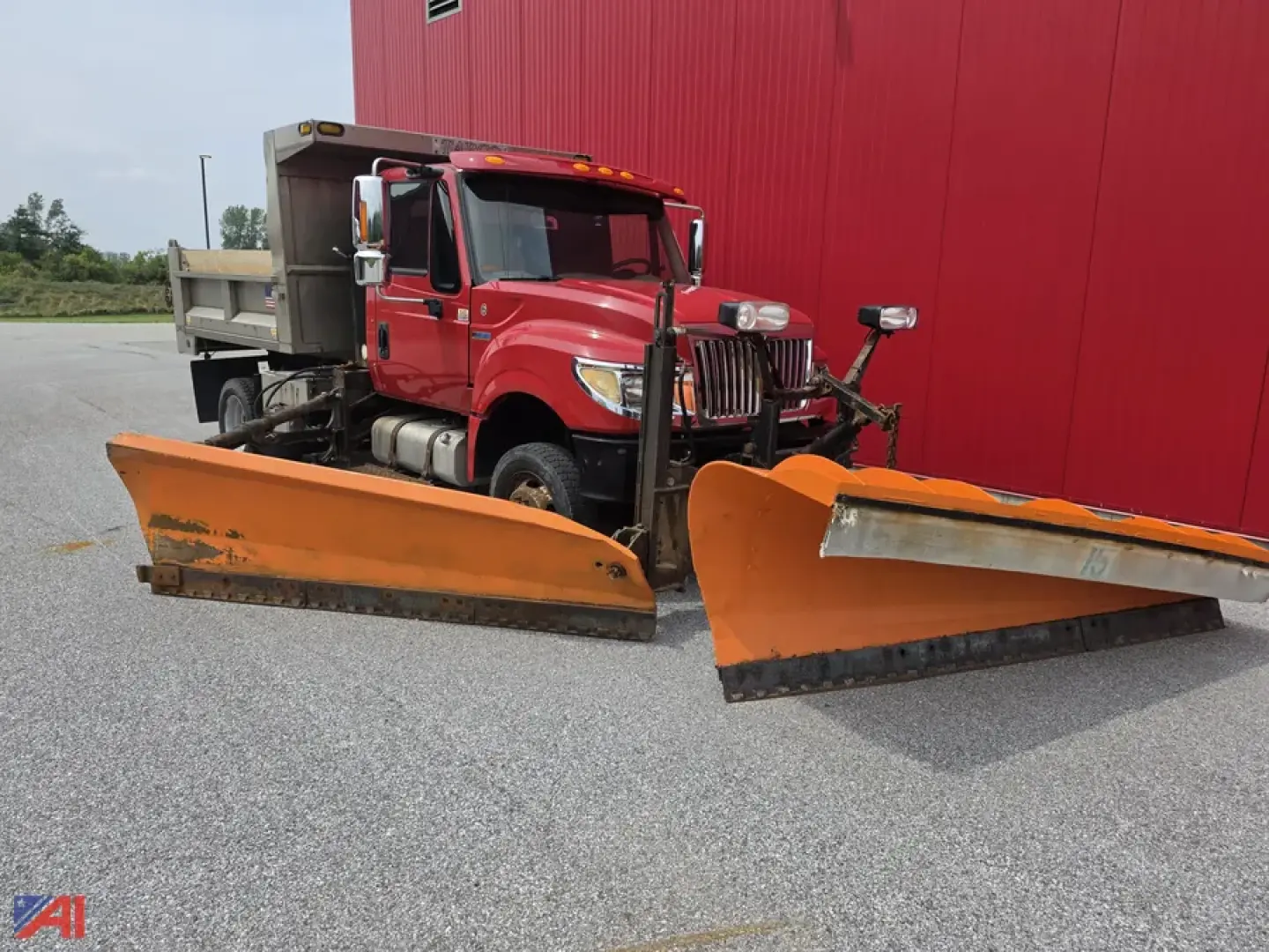 Dump truck with front-mounted orange plow blades, red International TerraStar cab, side view showing snowplow equipment.