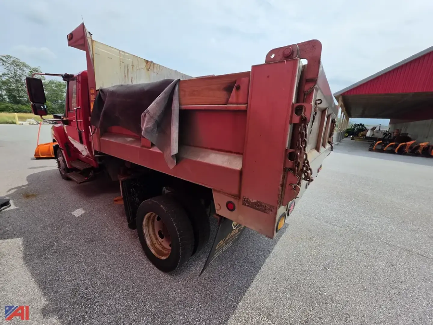 Dump truck bed with plow attachment, red International TerraStar dump truck, side view showing empty dump bed and rear tailgate with chains.