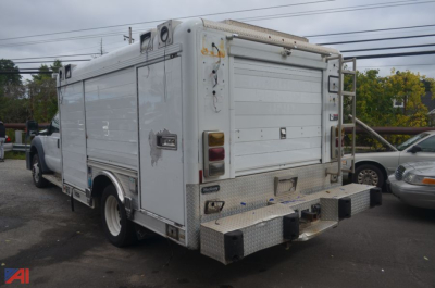 Ford F-550 dual rear wheel service body truck rear view showing metal utility compartments and rear bumper with step; aluminum diamond plate surfaces.