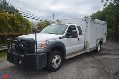 Ford F-550 utility truck with dual rear wheels and service body, front grille guard, white cab and utility compartments