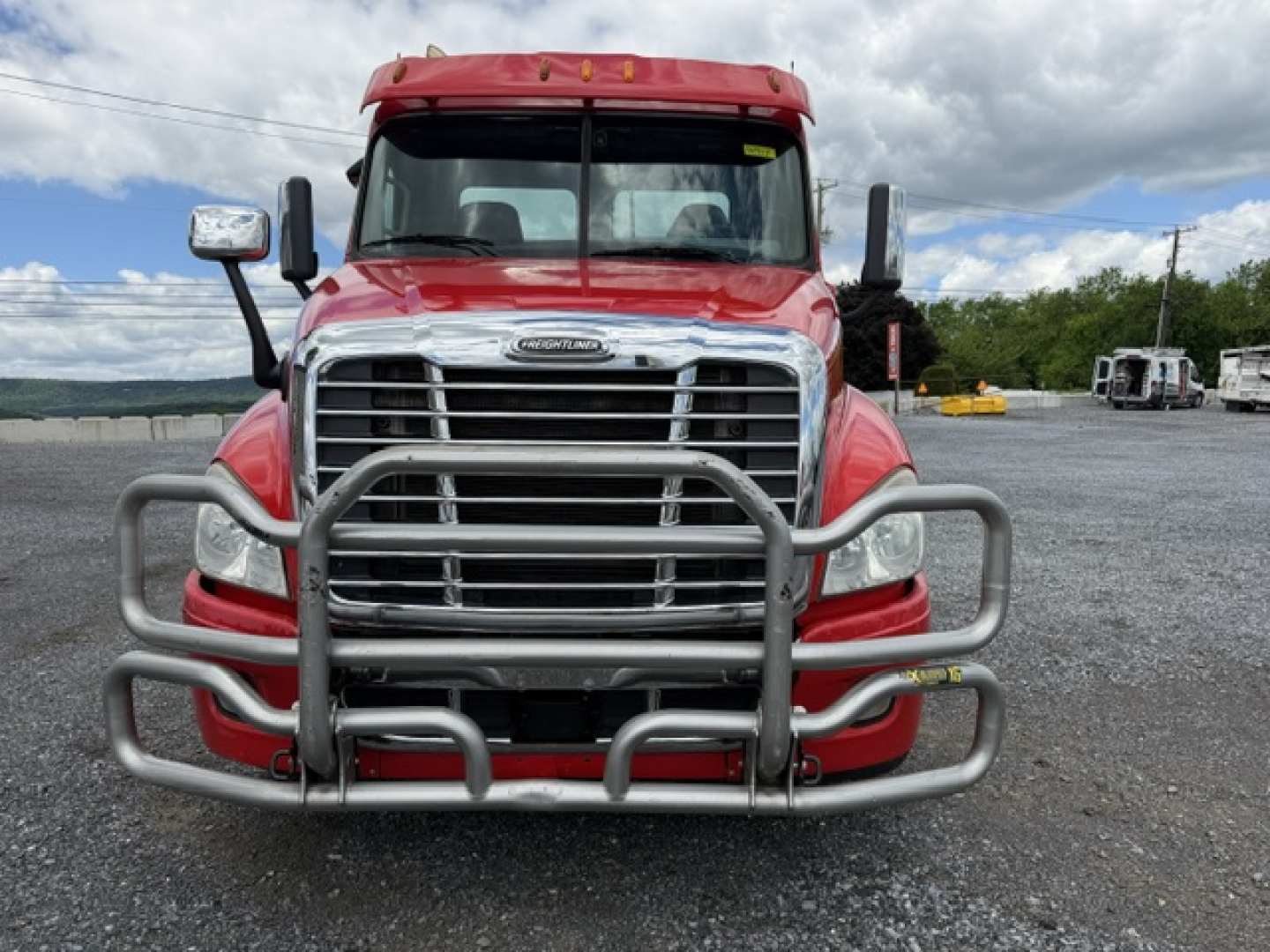 Front view of a red 2018 Freightliner Cascadia CA125DC with a large chrome grille and heavy-duty bull bar guard.
