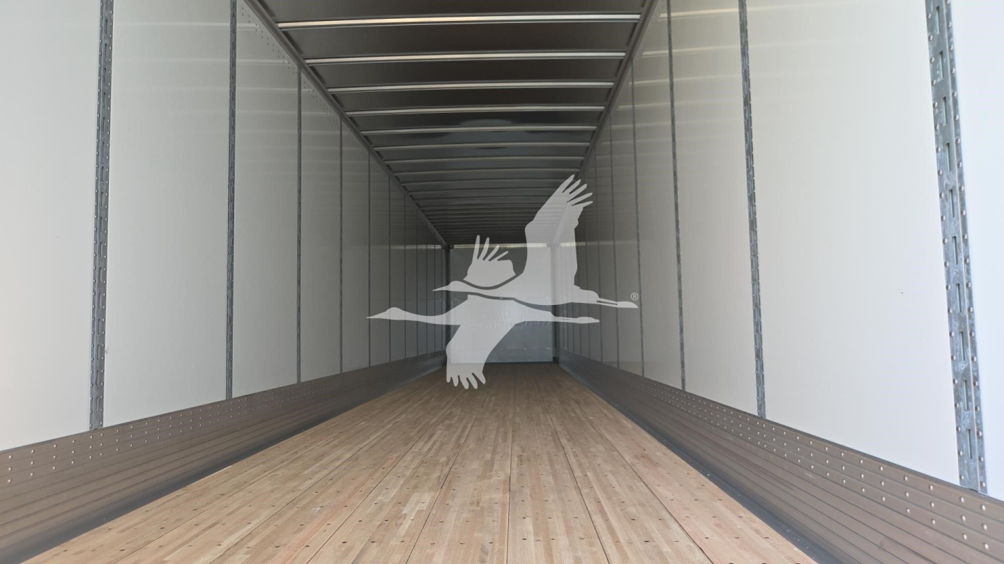 Trailer interior showing wooden floor and side walls of a cargo trailer, long perspective view