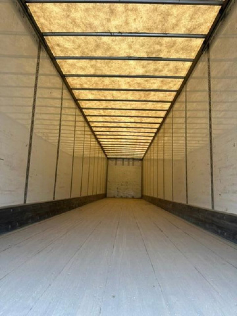 Trailer interior view showing empty cargo area with ribbed metal walls and a light panel ceiling.