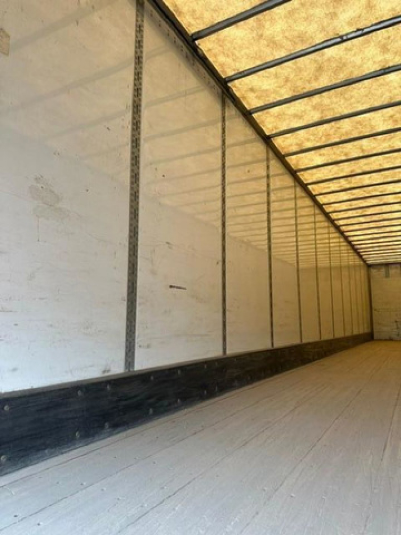 Trailer interior showing long white side walls with vertical posts and a wooden ceiling ridge, empty cargo area in a Wabash van trailer