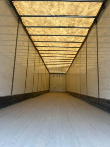 Trailer interior view showing empty cargo area with ribbed metal walls and a light panel ceiling.