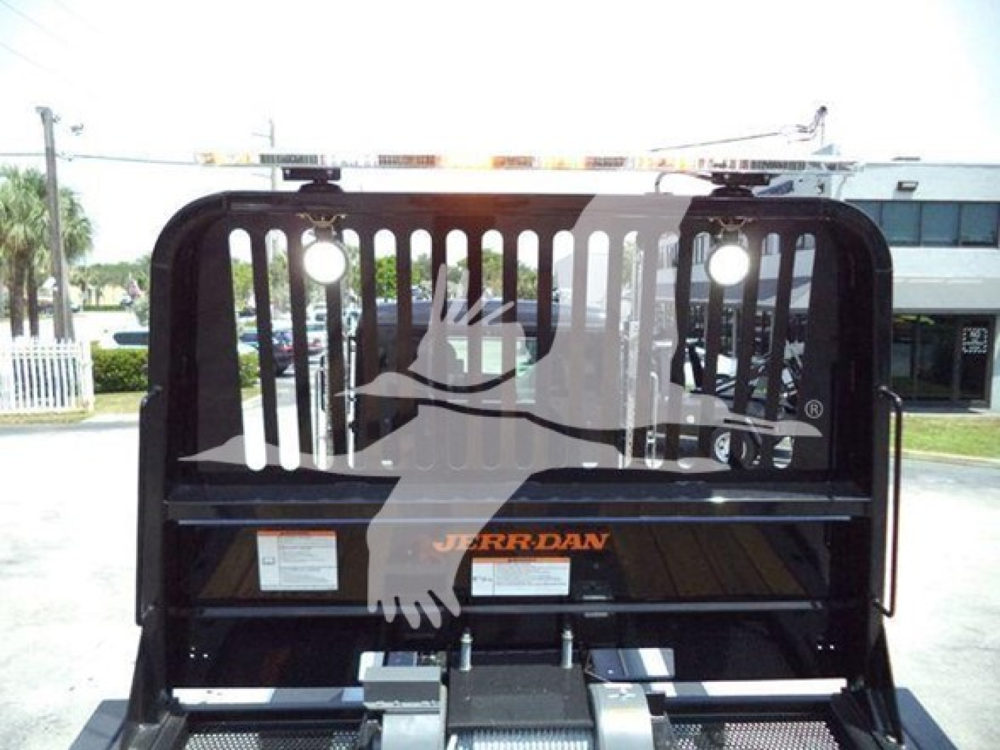 Truck bed with Jerr-Dan rollover carrier and graphic silhouette visible in the back of a Kenworth T880 rollback, rear view showing lift mechanism and branding.