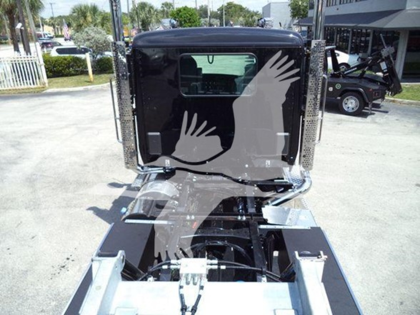 Kenworth T880 rollback truck cab rear view showing chrome bumper, rear window, and mounting hardware with cables in view.
