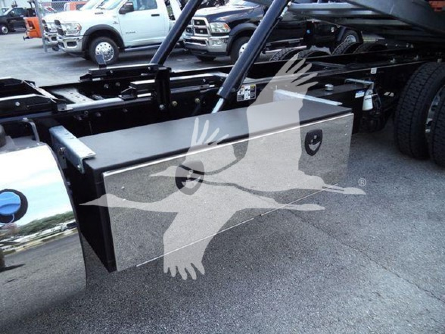 Kenworth T880 rollback chassis with a large rectangular metal toolbox mounted near the frame, side view showing storage box and chassis components.