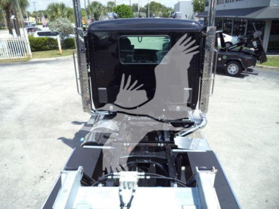 Kenworth T880 rollback truck cab rear view showing chrome bumper, rear window, and mounting hardware with cables in view.