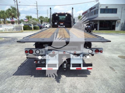 Truck chassis rear view showing rollback bed with hydraulic lines and taillights, Kenworth T880 platform truck.