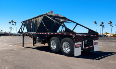 Trailer hopper with dual-axle wheels and raised end gate showing Gallegos branding and reflective tape.