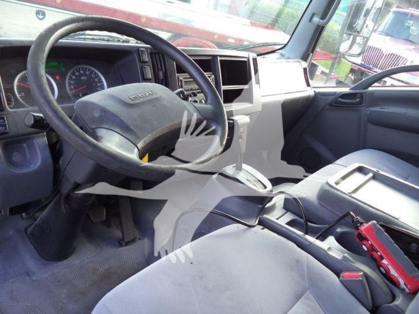 Isuzu NPR/Nrr truck cab interior showing steering wheel, dashboard, center console, and driver seat with tools.