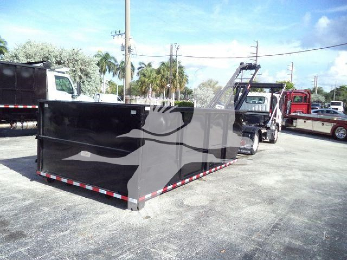 Isuzu NPR/Nrr rolloff truck bed with black container and hydraulic lift in yard.
