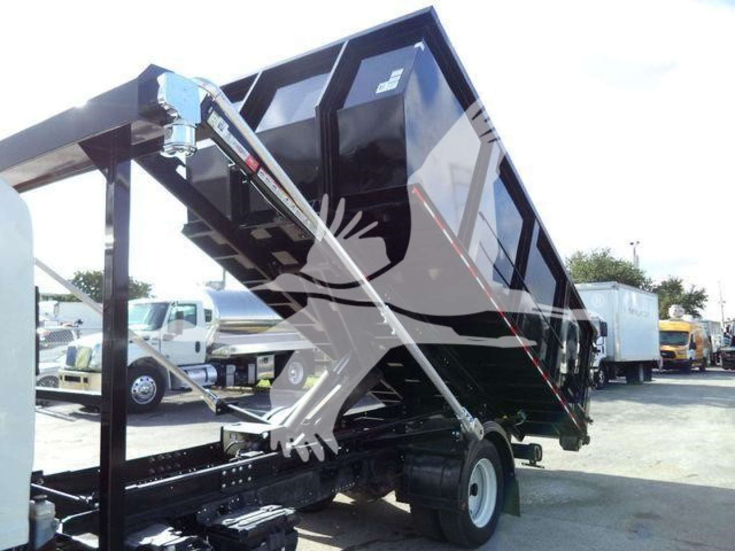 Isuzu NRR rolloff truck rear view with tipped dump bed and hydraulic hoist, no legible labels visible on body in this image.