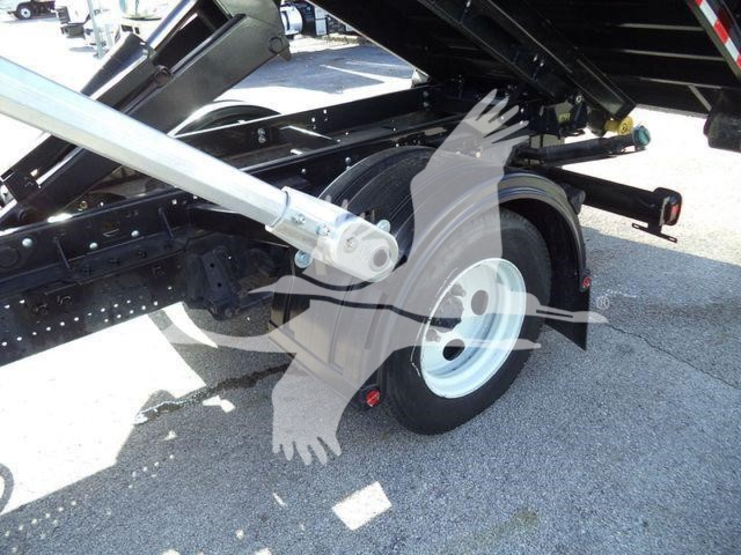 Isuzu NPRR truck wheel and hydraulic lift arm in the bed, view of rear wheel and supporting frame.