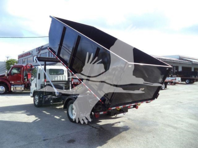Isuzu NPR truck with a raised dump bed in a deployment lot showing side view of chassis and hydraulic mechanism.