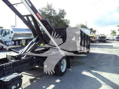 Isuzu NPRR roll-off truck body with hydraulic hoist in operation, side view showing cargo container and rear wheel.