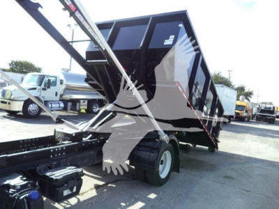 Isuzu NPR-style roll-off truck with raised dump bed showing hydraulic cylinder and hitch area, faint stickers on cabin window, no visible legible text.