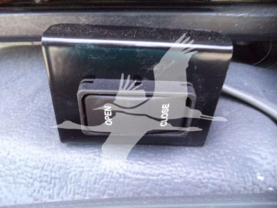 Isuzu NPRR cargo area view showing a black switch labeled OPEN/CLOSE with a textured dashboard surface.