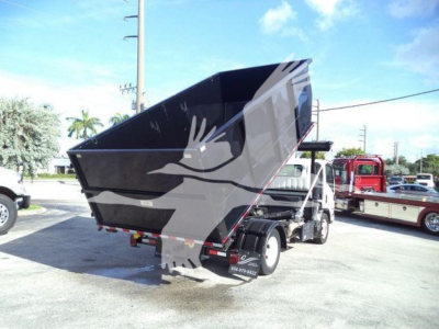 Isuzu NRR roll-off truck with dump bed raised, side view showing rear wheels and chassis.