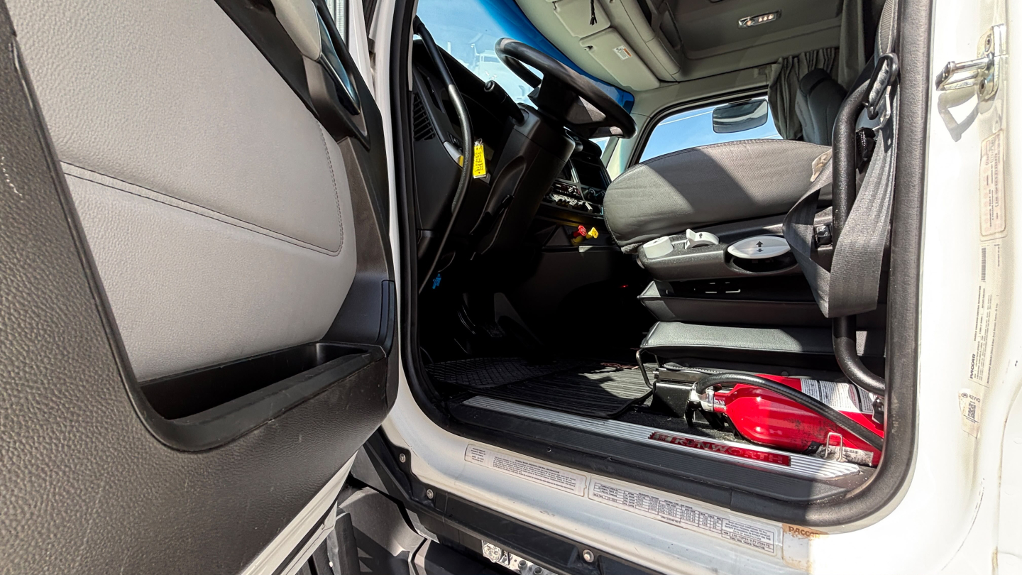 Kenworth T680 cab interior and entry shown from driver's side door open, dashboard and seat visible.