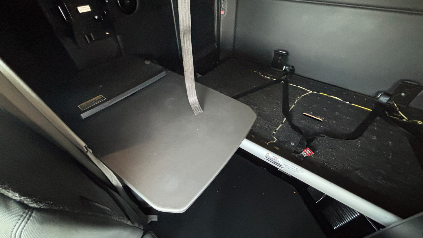 Kenworth T680 cabin interior showing a fold-out sleeper tray/table with surrounding floor and seat rails visible.
