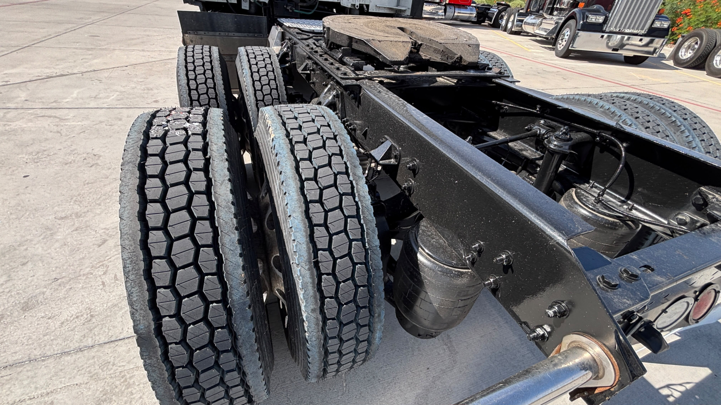 Kenworth T680 chassis with dual rear axles and wheel twin tires; view of frame, suspension, and drivetrain area showing black painted frame and components.