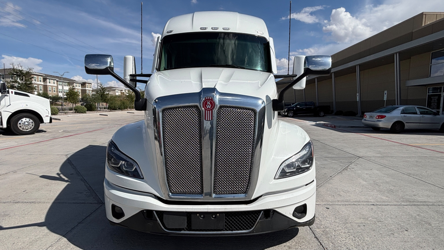 Kenworth T680 truck front view showing bold grille and headlights under clear sky.