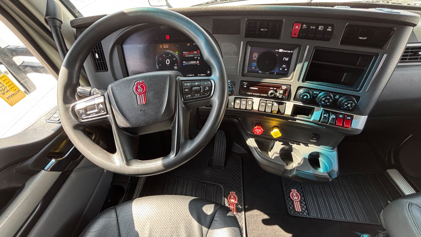 Kenworth T680 truck interior dashboard and steering wheel showing controls and gear shift.