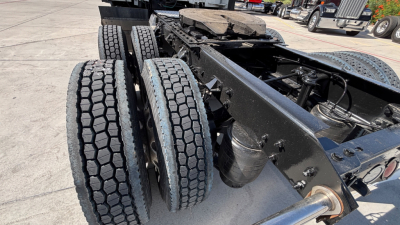 Kenworth T680 chassis with dual rear axles and wheel twin tires; view of frame, suspension, and drivetrain area showing black painted frame and components.