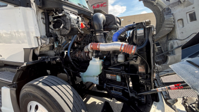 Kenworth T680 engine bay showing compact turbo and hoses, coolant reservoir, and exposed components
