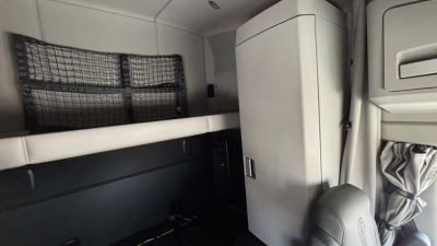 Kenworth T680 sleeper cab interior showing overhead bunk and storage cabinet.