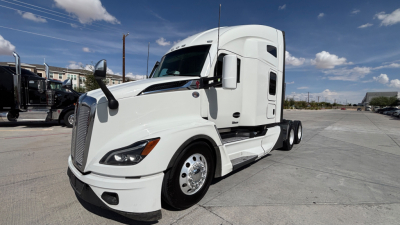 Kenworth T680 sleeper cab tractor in white, front-left angle, showing aerodynamic hood, headlights, side mirrors, and dual rear axles.