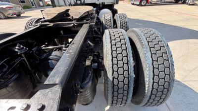 Trucks chassis rear view showing dual rear axles and tires, metal frame with suspension components and fifth wheel area visible.