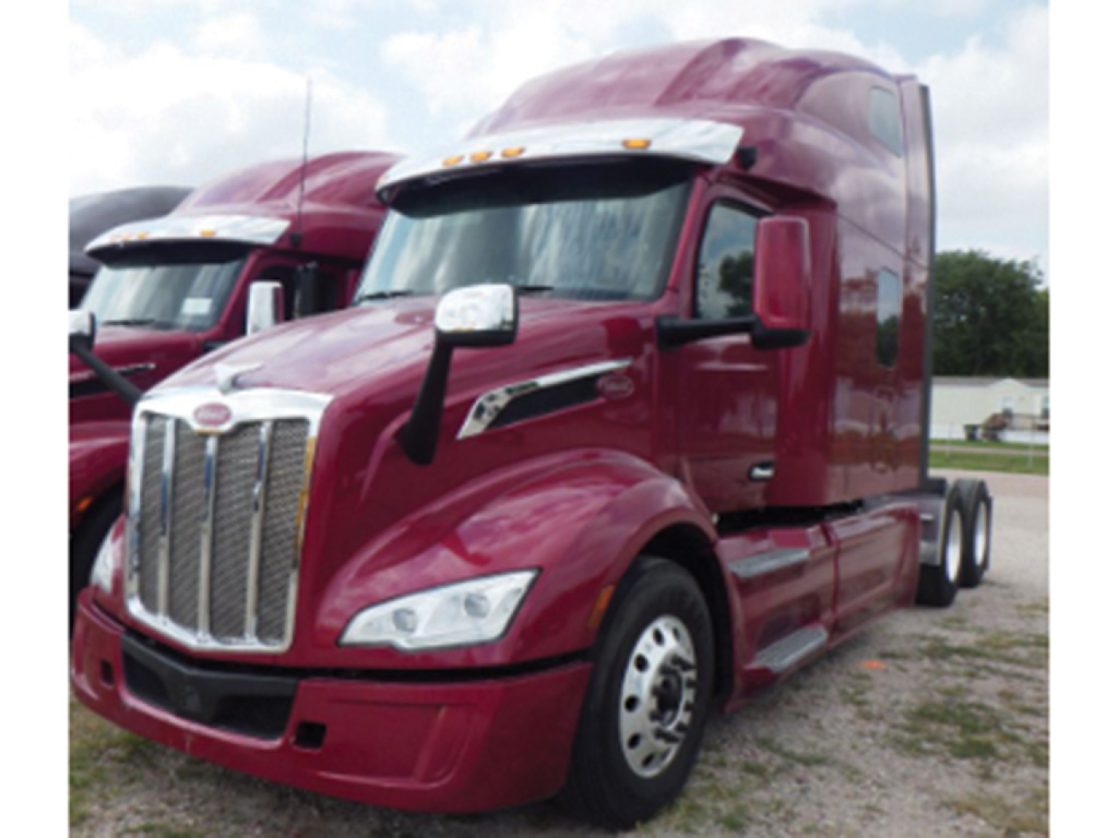 Peterbilt 579 conventional sleeper truck, maroon color, front three-quarter view showing grille, headlights, and side mirror.