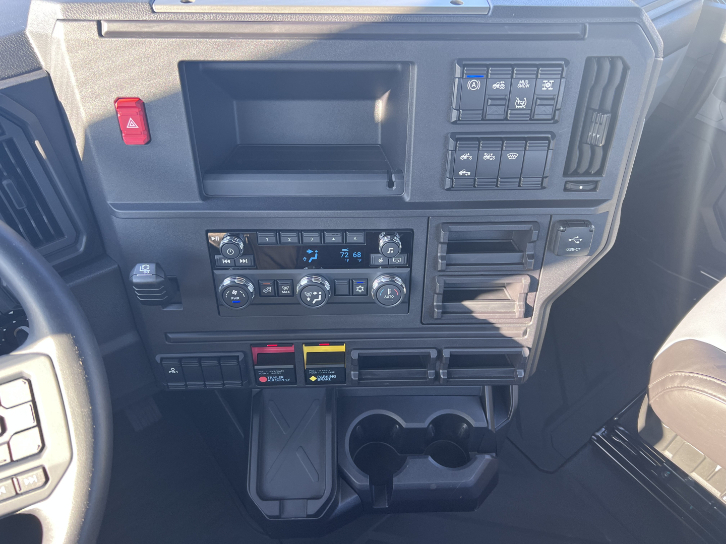Dashboard panel of a Mack AN64T daycab showing controls, HVAC, cup holders, and storage compartments.