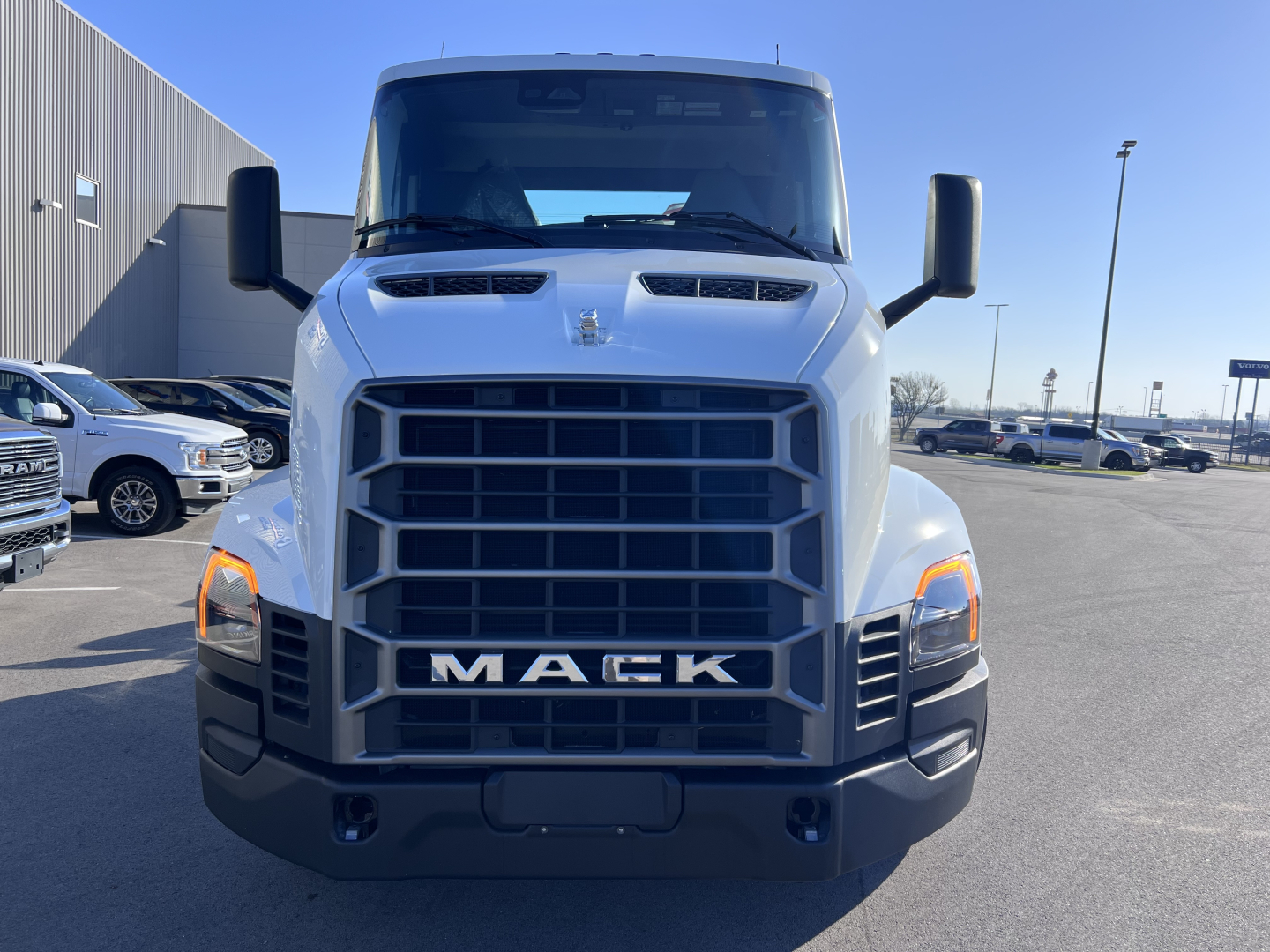 Front view of a white 2027 Mack AN64T conventional daycab truck showing large black grille, Mack lettering, dual hood scoops, and rectangular headlights.