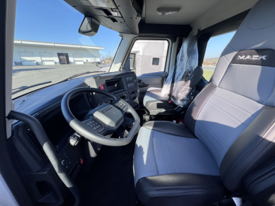 Mack AN64T truck cab interior showing steering wheel, dashboard, and driver seat with protective plastic.