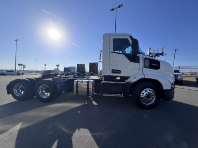 Conventional daycab Truck chassis with white cab, side view showing front wheels and fuel tanks, no trailer attached.