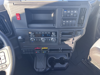Dashboard panel of a Mack AN64T daycab showing controls, HVAC, cup holders, and storage compartments.